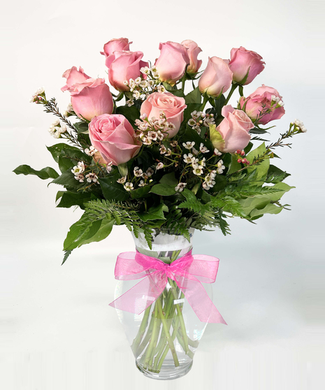 One dozen long stemmed pink roses in a clear glass vase.
