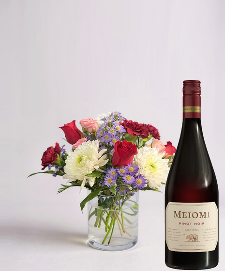 Red cube vase filled with roses in red, pink and lavender with greenery.