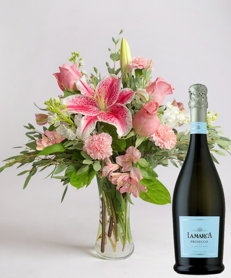 Red cube vase filled with roses in red, pink and lavender with greenery.