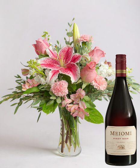 Red cube vase filled with roses in red, pink and lavender with greenery.