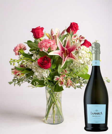 Red cube vase filled with roses in red, pink and lavender with greenery.