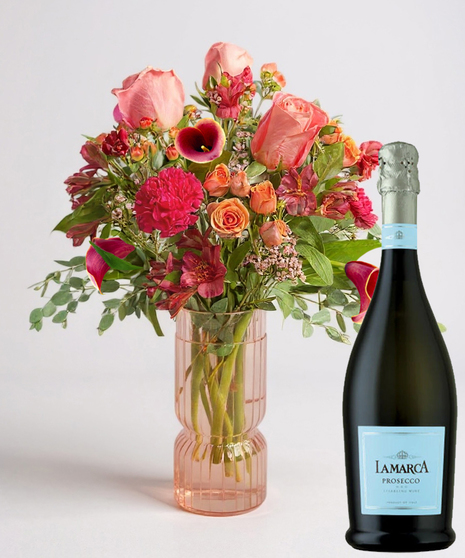 Red cube vase filled with roses in red, pink and lavender with greenery.