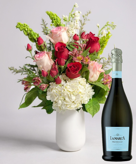 Red cube vase filled with roses in red, pink and lavender with greenery.