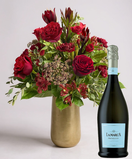 Red cube vase filled with roses in red, pink and lavender with greenery.