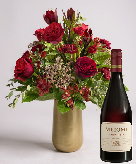 Red cube vase filled with roses in red, pink and lavender with greenery.