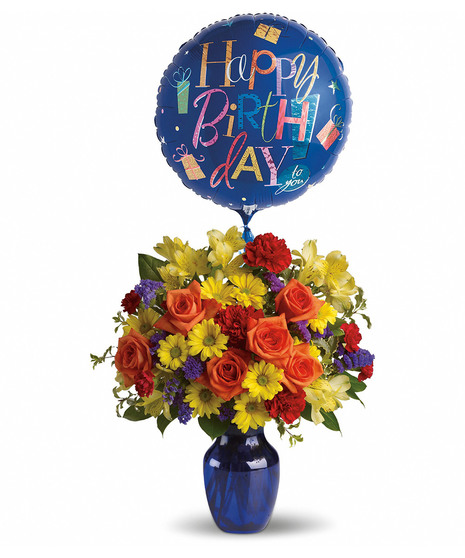 Cobalt blue vase filled with red, orange, yellow and purple flowers with a happy birthday mylar balloon.