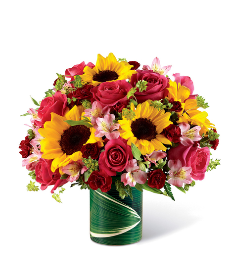 Sunflowers, pink roses and alstroemeria, and mini burgundy carnations in a ceramic illusion vase. 