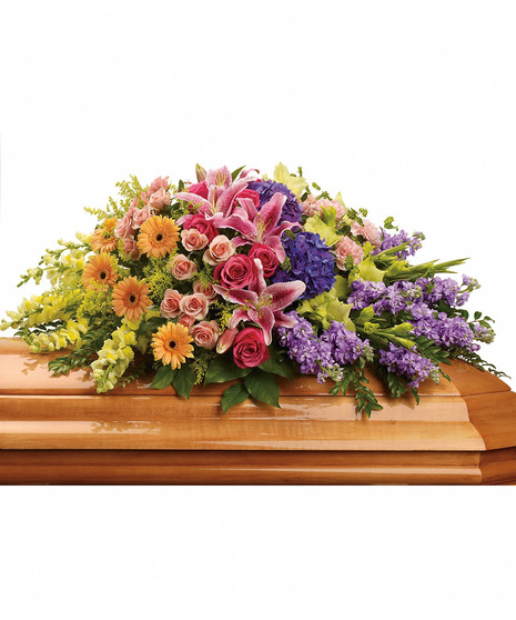 Bright casket spray of roses, lilies and more with greenery. 