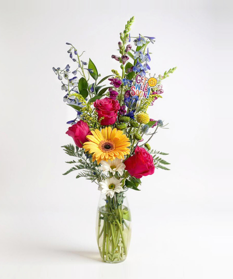 Sunflowers, hydrangea and more in a clear glass vase. 