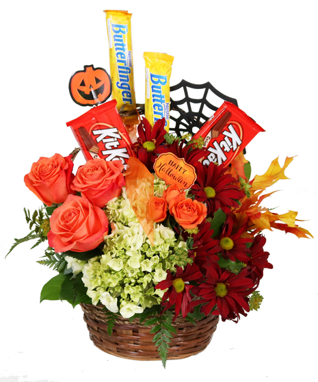 Basket filled with red daisies, oragnge roses, green hydrangea, fall leaves and Halloween treats.