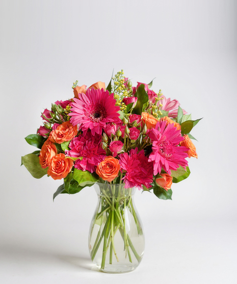 Vibrant orange & pink roses in a clear glass vase.