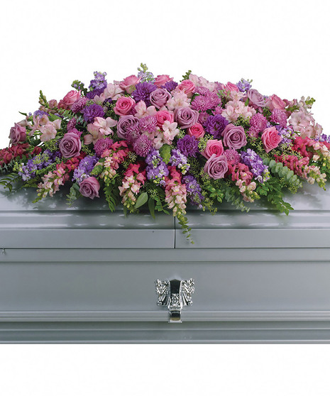 Casket spray of lavender and pink flowers with greenery. 