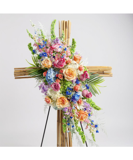 Sympathy wreath of pastel pink, peach and purple flowers with coordinating ribbon. 