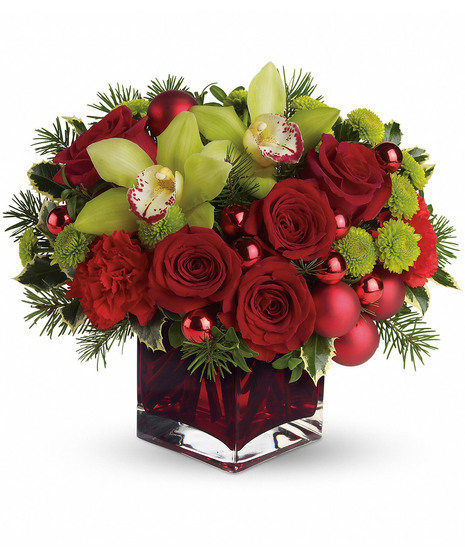 Red cube vase of red roses, ornament balls and douglas fir. 