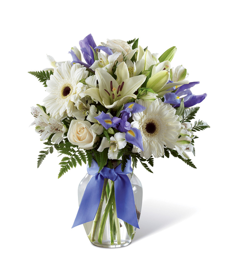 Hanukkah bouquet of blue and white flowers in a clear glass vase tied with blue ribbon.