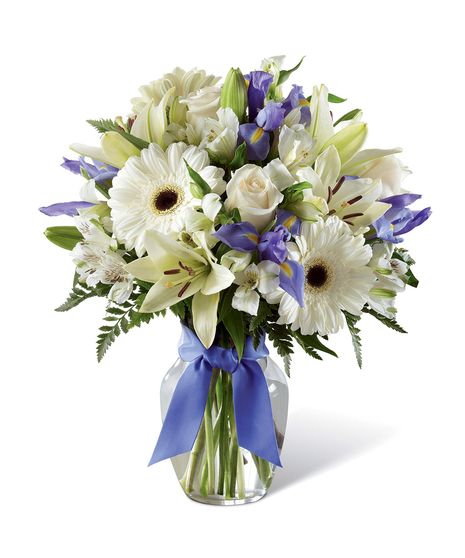 Hanukkah bouquet of blue and white flowers in a clear glass vase tied with blue ribbon.