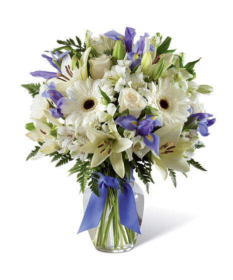 Hanukkah bouquet of blue and white flowers in a clear glass vase tied with blue ribbon.
