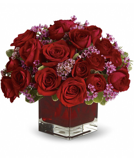 Eighteen red roses and lavender accents in a red glass cube vase. 