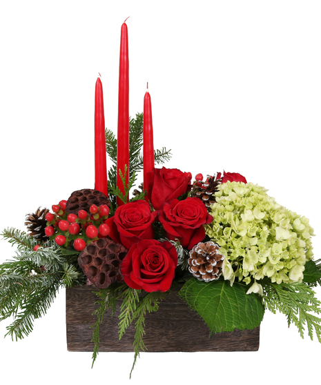 Holiday centerpiece of red and white flowers, berries, pine cones and more in a wooden box with red taper candles.