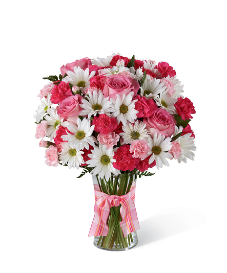 Fuchsia and pink mini carnations, hot pink roses, white daisies and greenery in a clear glass vase tied with pink ribbon. 