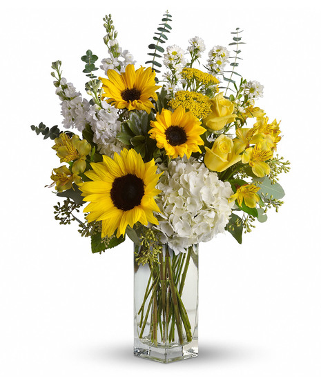 Sunflowers, hydrangea and more in a clear glass vase. 