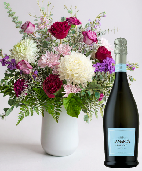 Red cube vase filled with roses in red, pink and lavender with greenery.