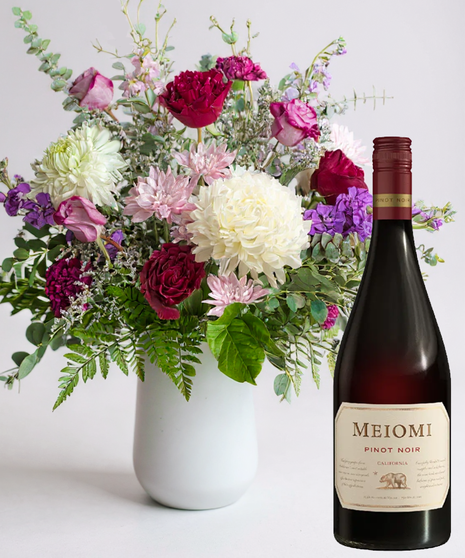 Red cube vase filled with roses in red, pink and lavender with greenery.