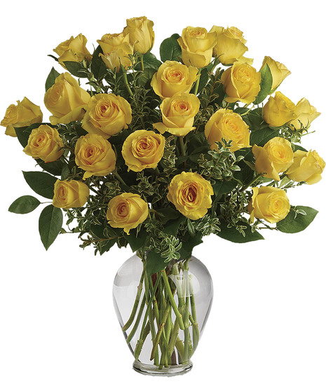 Bright yellow roses with seeded eucalyptus in a clear glass vase. 