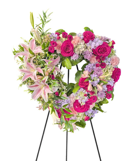 Sympathy wreath of pastel pink, peach and purple flowers with coordinating ribbon. 