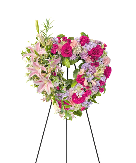 Sympathy wreath of pastel pink, peach and purple flowers with coordinating ribbon. 