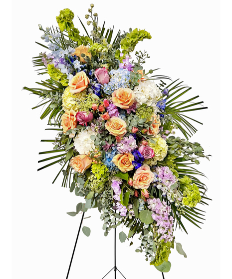 Sympathy wreath of pastel pink, peach and purple flowers with coordinating ribbon. 
