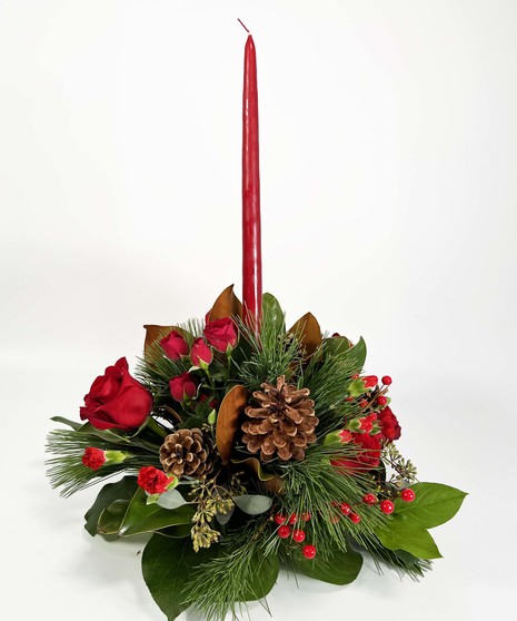 Holiday centerpiece of greenery, red roses, pine cones, berries and a red center candle. 