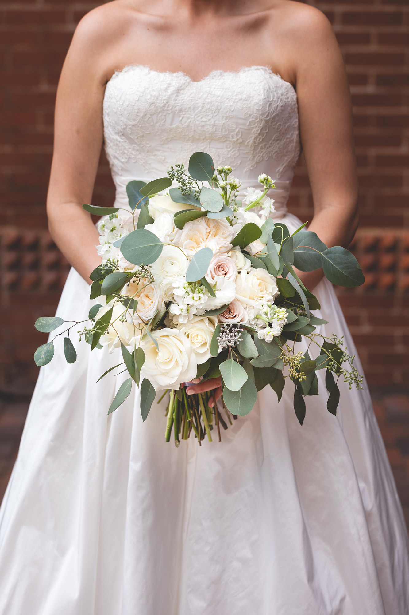 A bride holds a beautiful bouquet of white and pink roses